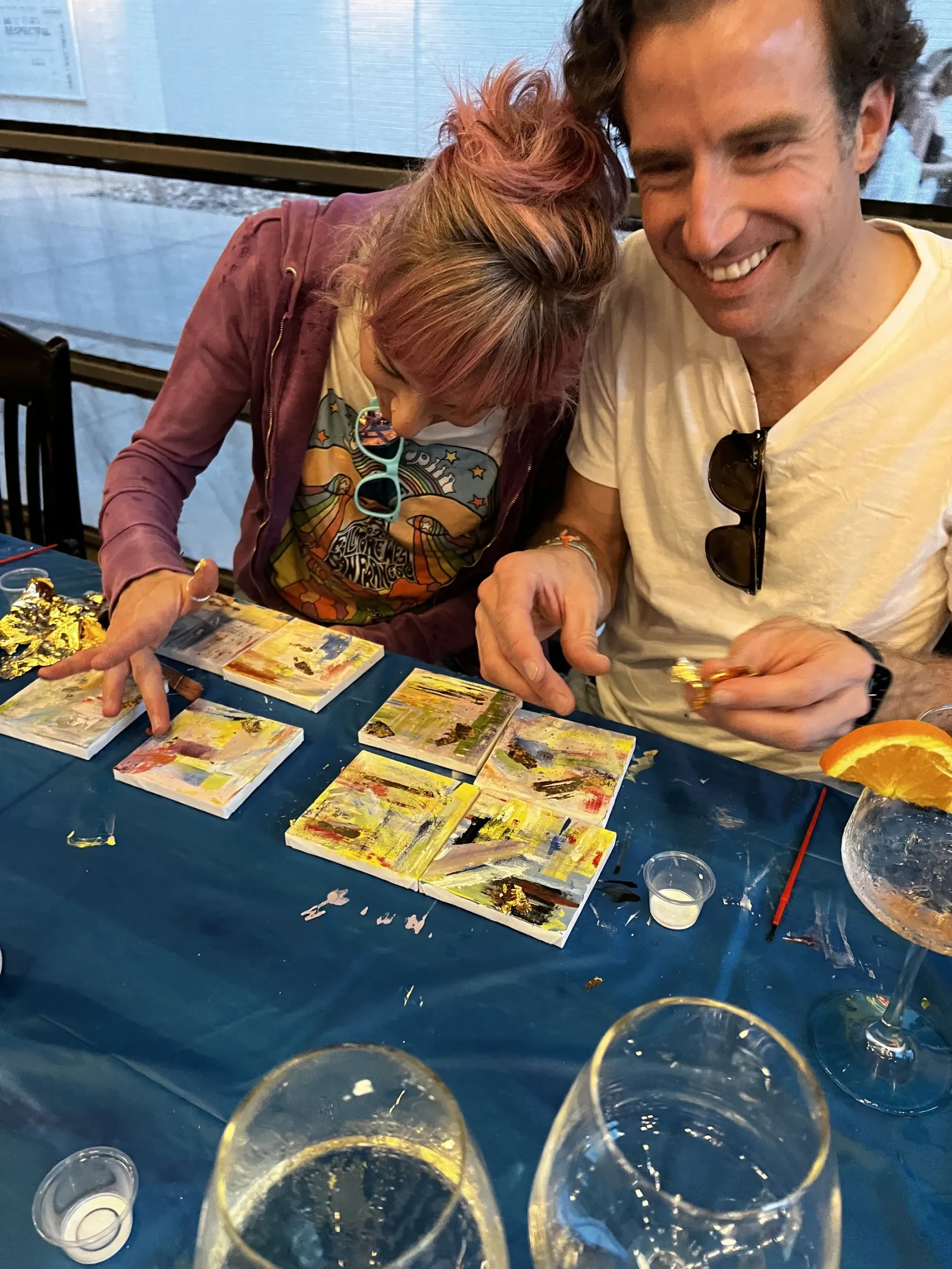 A couple laughing over their gilded mini canvases at a class