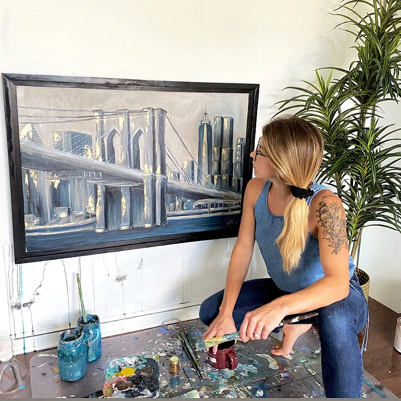 Kelly with a framed Brooklyn Bridge painting
