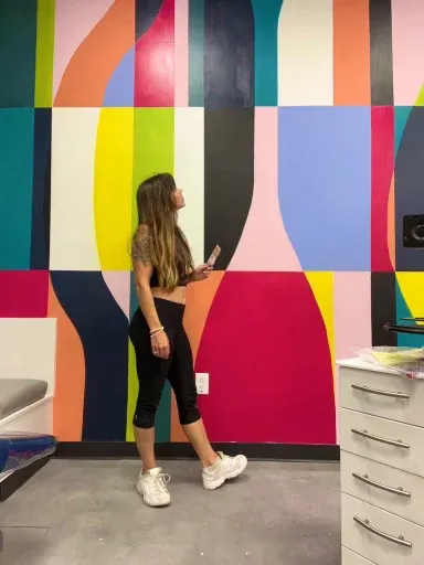 Kelly in front of a bold color-block geometric wall