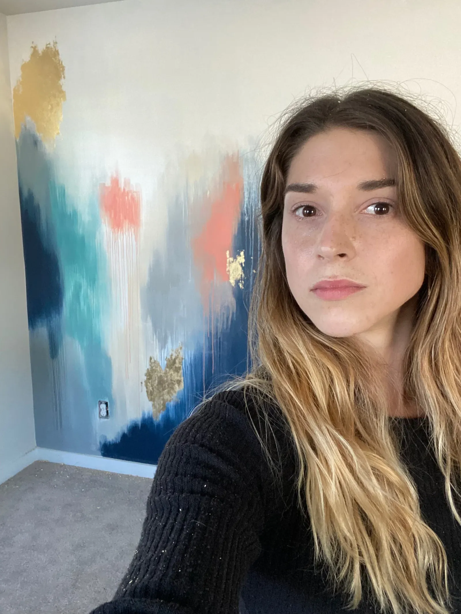 Kelly in front of a navy, teal and coral abstract wall