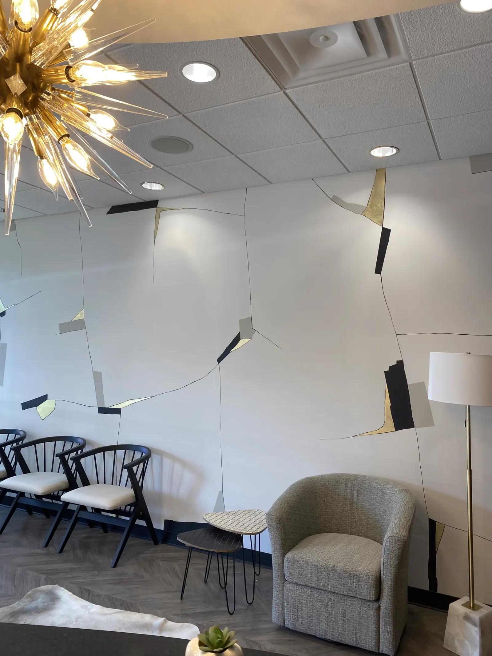 White lounge with black and gold leaf lines across the walls